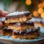 Served date candy bars stacked on a plate with coconut topping