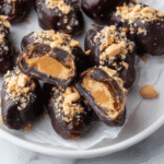 Date Snickers on a rustic plate with chocolate and peanuts