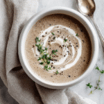 Creamy Mushroom Soup top-down view in a bowl with cream and thyme