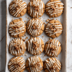 Maple Brown Sugar Cookies arranged on a baking sheet with maple icing and pecans